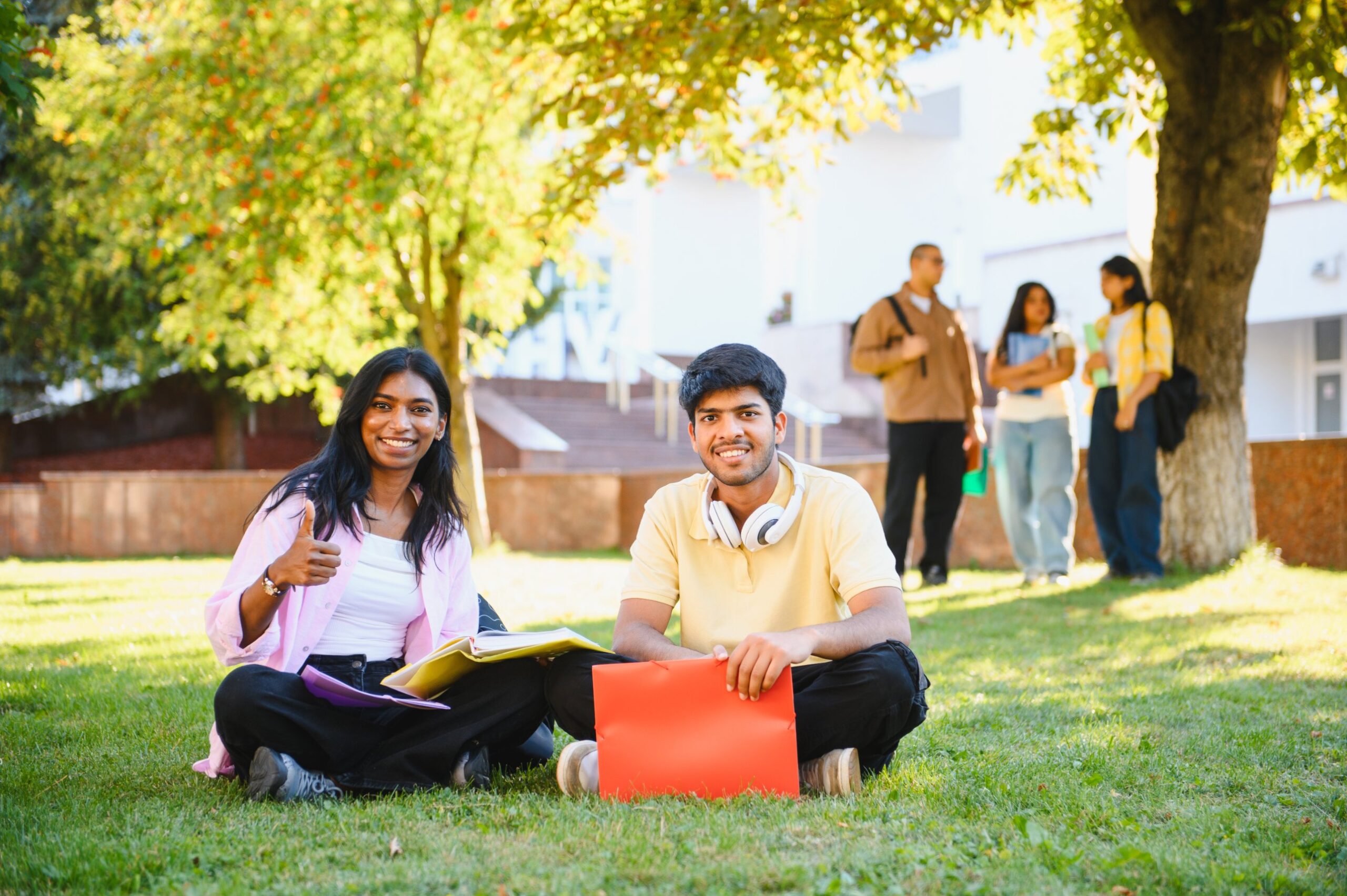 Students smiling on campus, thumbs up